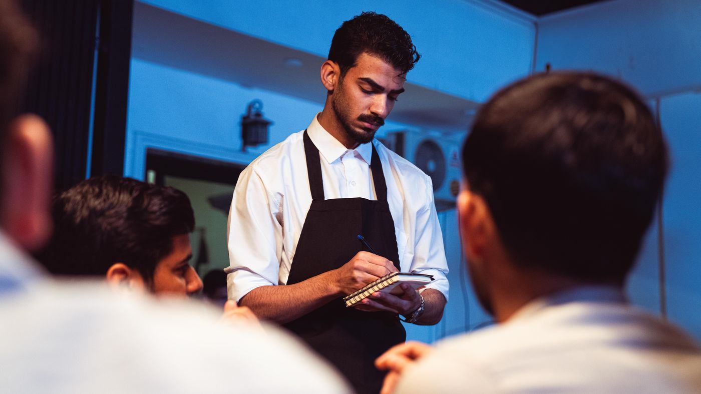 A server taking a customer’s order at the table