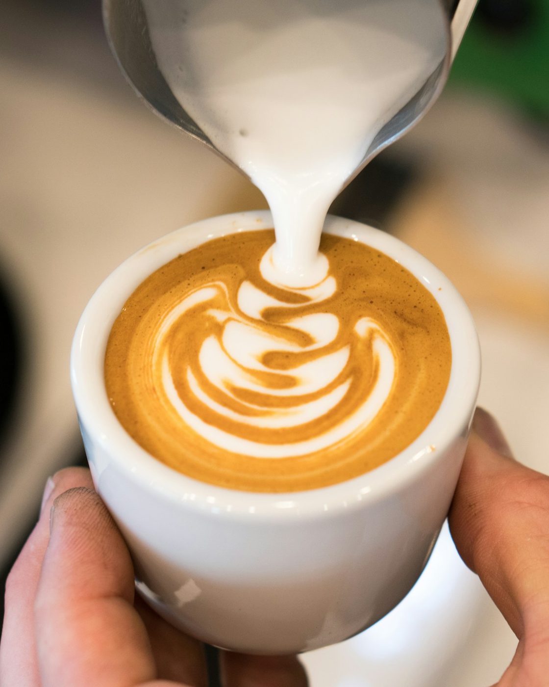 Steamed milk being poured into an espresso to make a tulip
