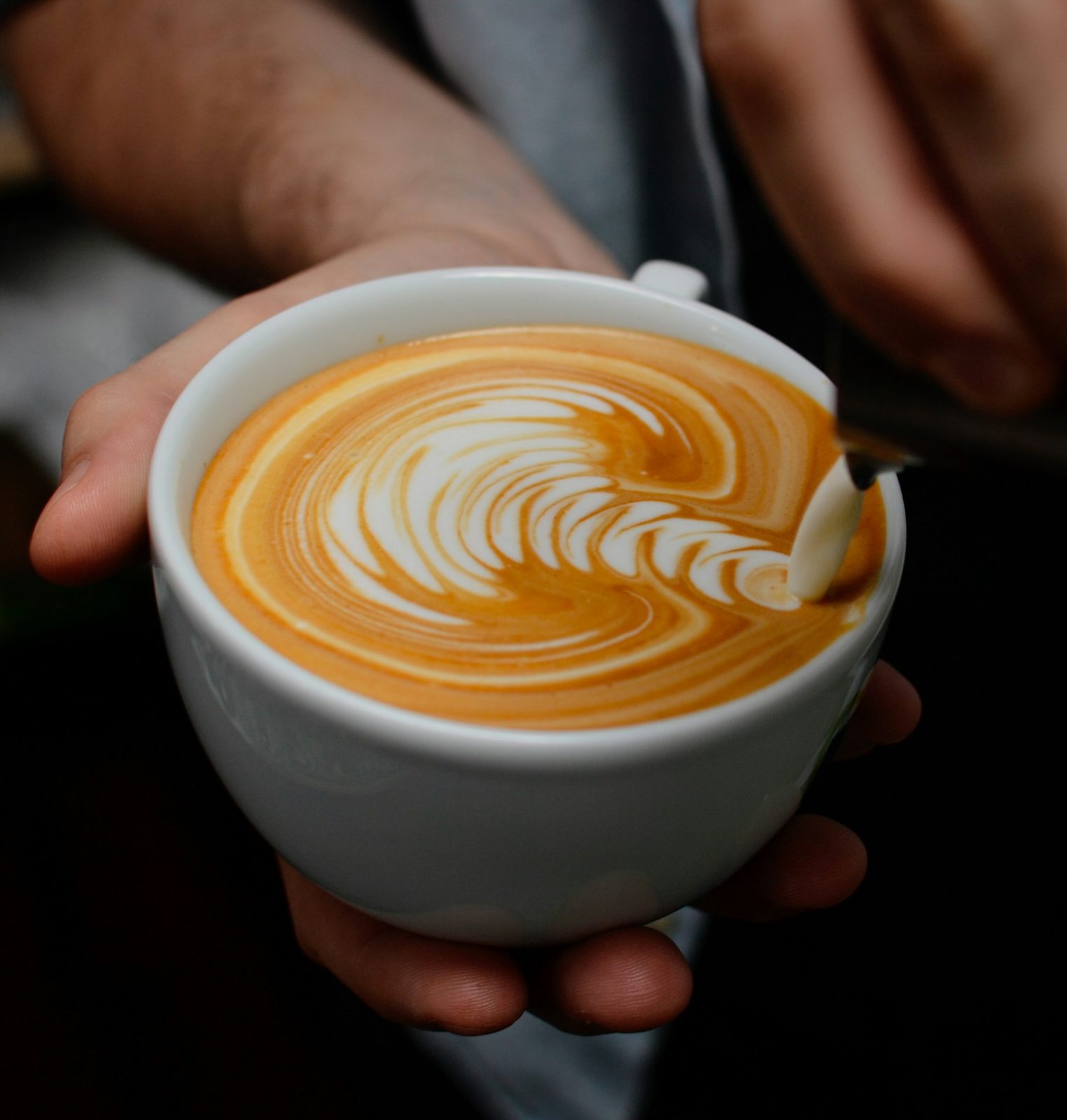 A barista pouring a rosetta into a cappuccino