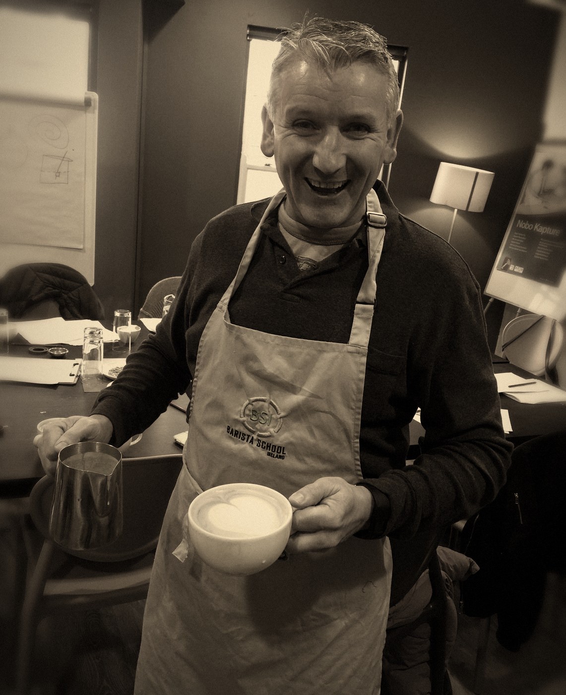 A smiling student holding a latte he poured