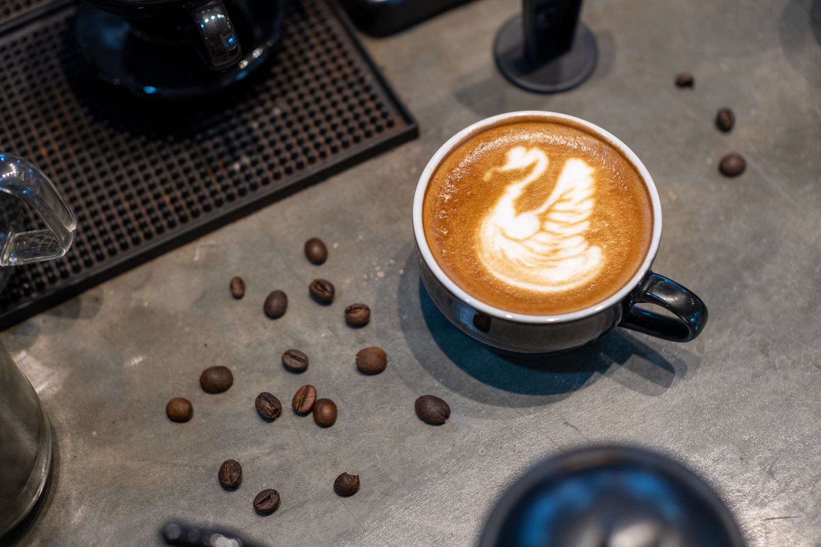 Swan latte art in a dark mug on a concrete bar
